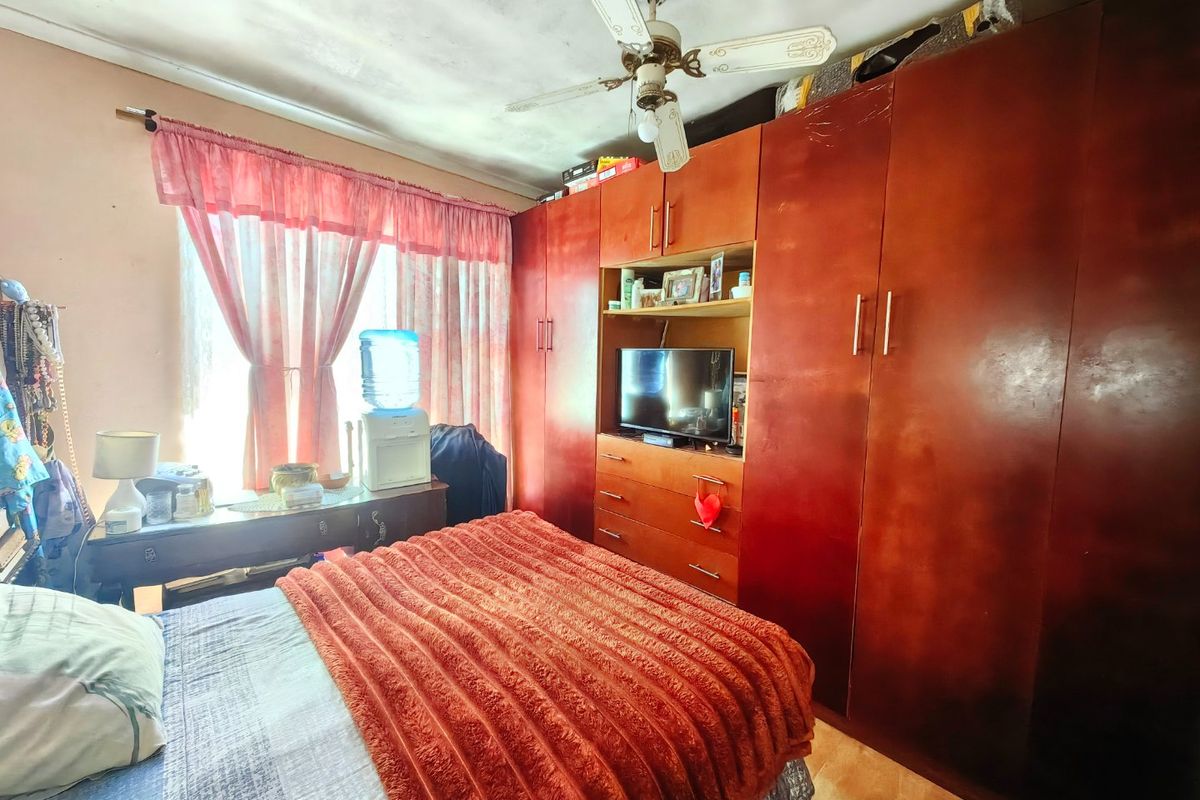 Bedroom featuring a large built-in wardrobe, ceiling fan, and tiled flooring. The ceiling shows visible signs of water staining and wear.