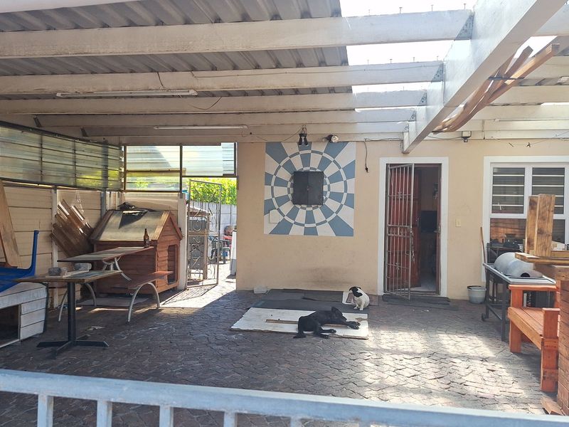 A covered outdoor patio area featuring paved flooring and a timber roof structure, offering potential for renovation into an inviting entertainment space.