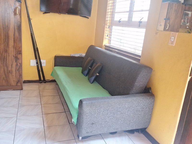 A living area featuring tiled flooring, built-in cabinetry, and venetian blinds, providing a functional space with potential for cosmetic updates.