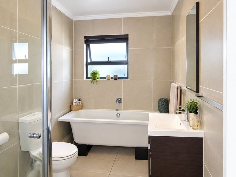 A well-maintained bathroom featuring a freestanding bathtub, modern vanity with basin, toilet, and a separate shower enclosure with neutral wall and floor tiling.