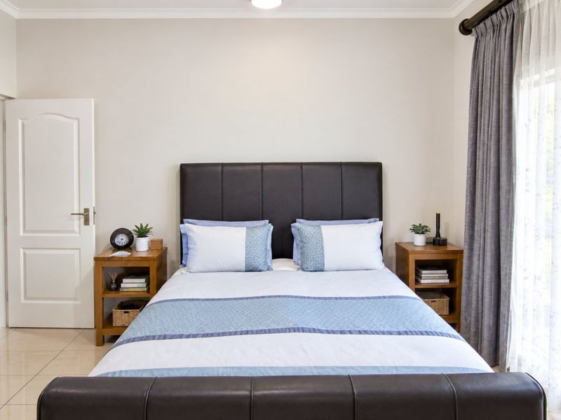 A well-maintained bedroom featuring neutral wall tones, tiled flooring, and classic architectural detailing including cove cornicing.