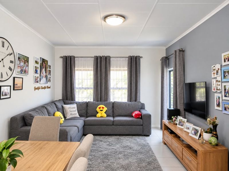 A well-maintained living room featuring tiled flooring, neutral wall tones, and large windows with curtain rods, providing a bright and comfortable living space.