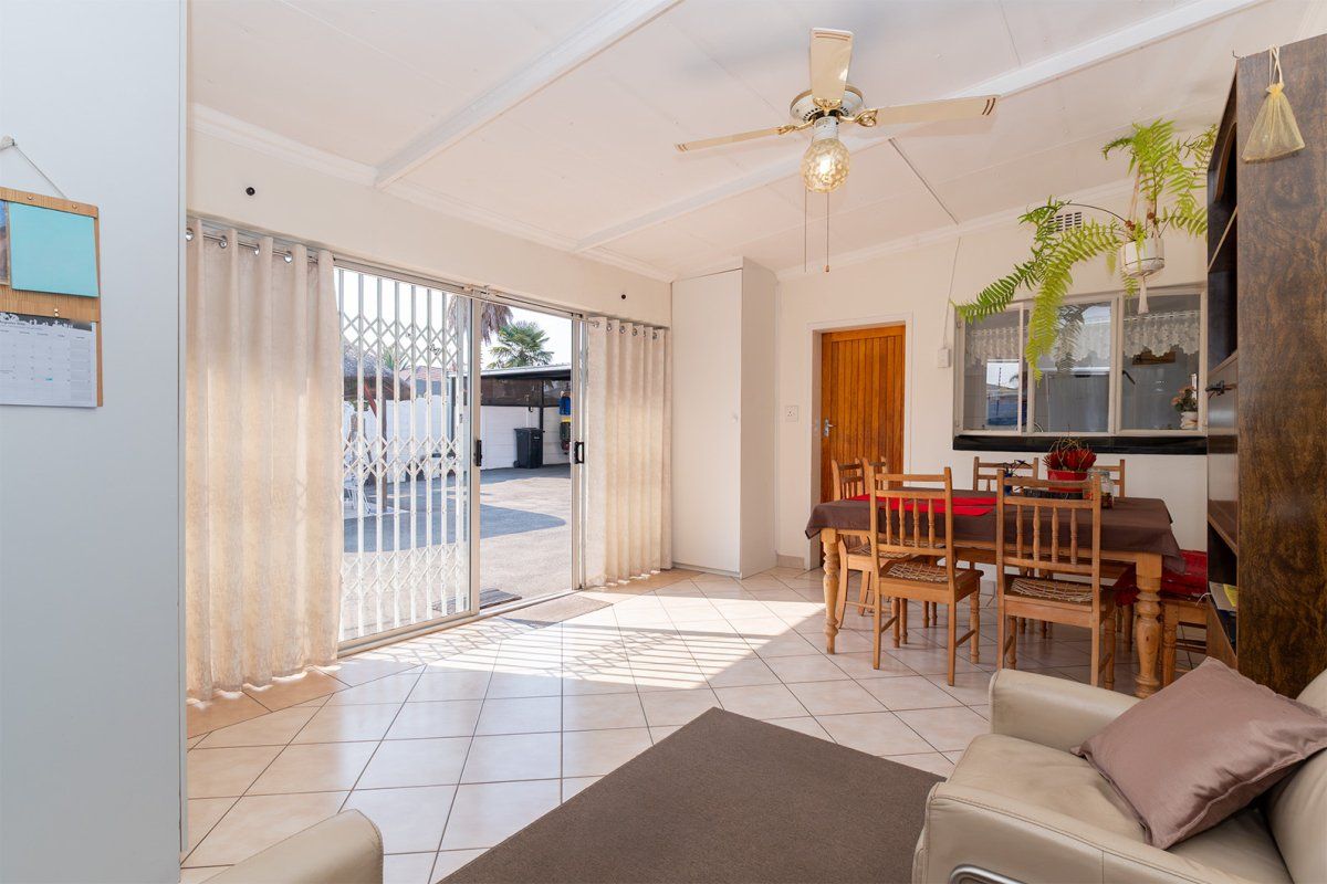 A bright living area featuring tiled flooring, a ceiling fan, and large sliding glass doors providing direct access to the outdoor space.
