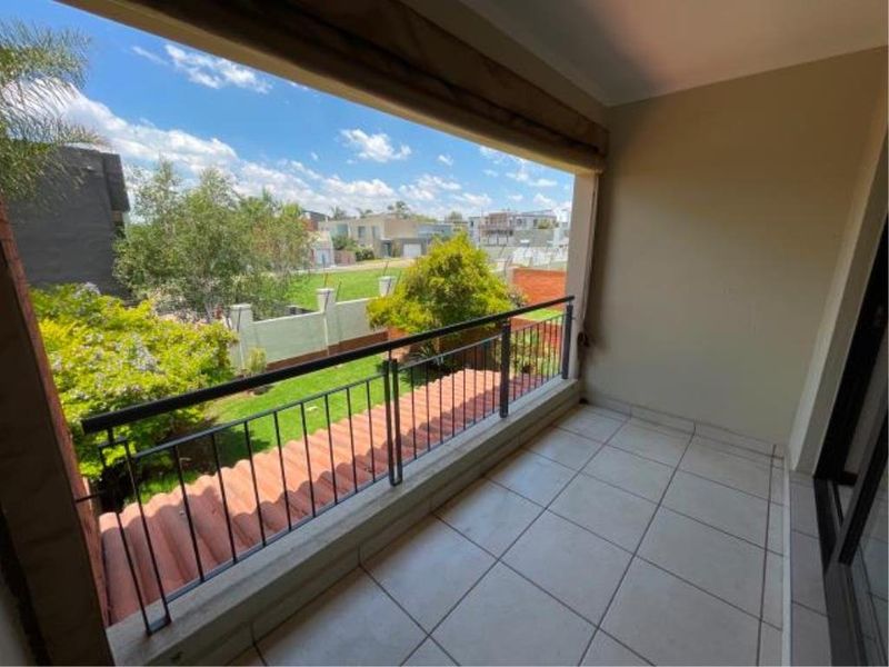 A covered balcony featuring tiled flooring and a metal balustrade, offering an elevated view over the garden and surrounding neighbourhood.