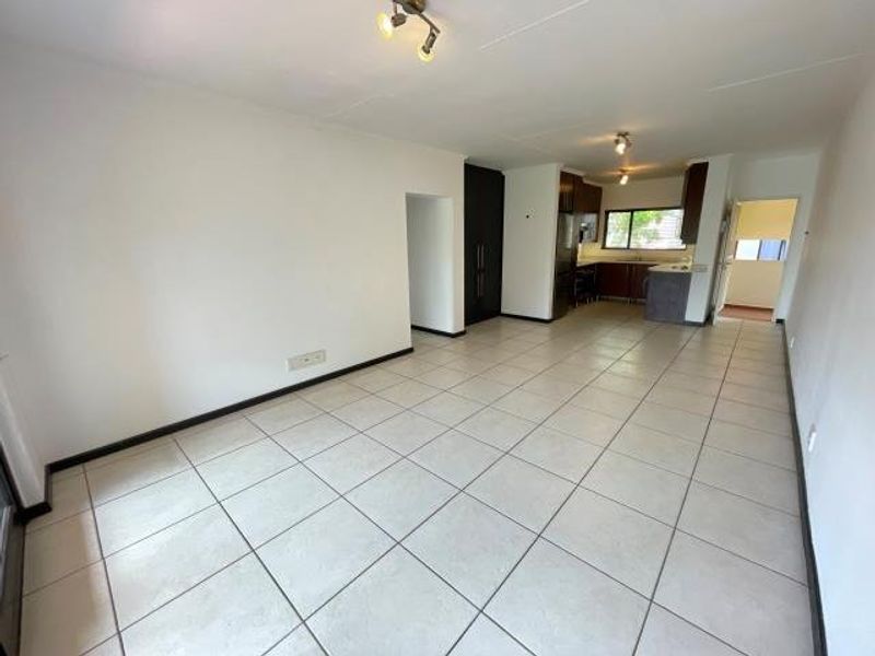 Spacious open-plan living area featuring neutral tiled flooring and an integrated kitchen with built-in cabinetry and fixtures.