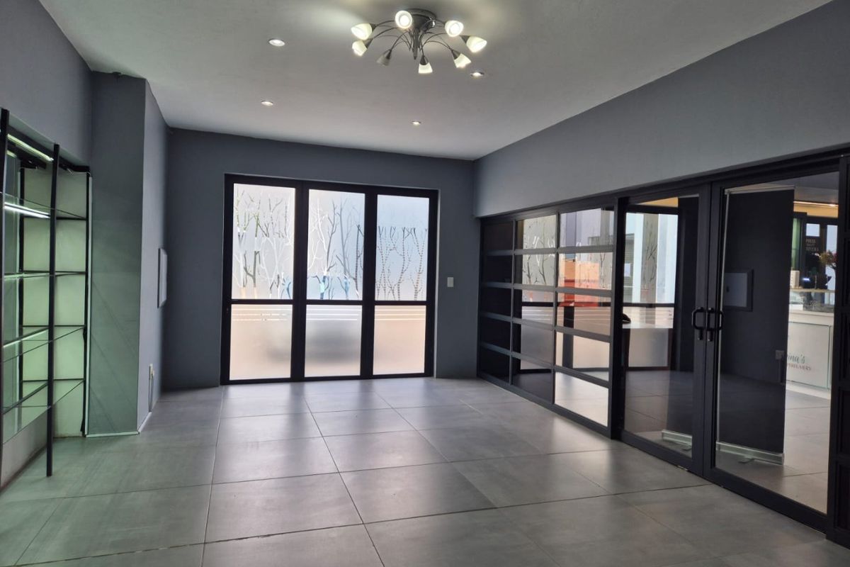 Modern commercial office space featuring large format floor tiles, glass partitions, and contemporary lighting, offering a clean and professional environment.