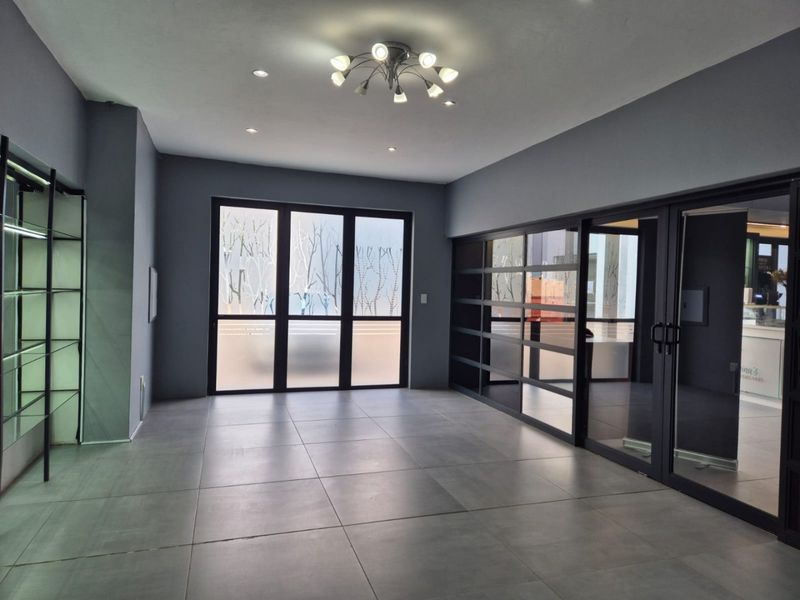 Modern commercial office space featuring large format floor tiles, glass partitions, and contemporary lighting, offering a clean and professional environment.