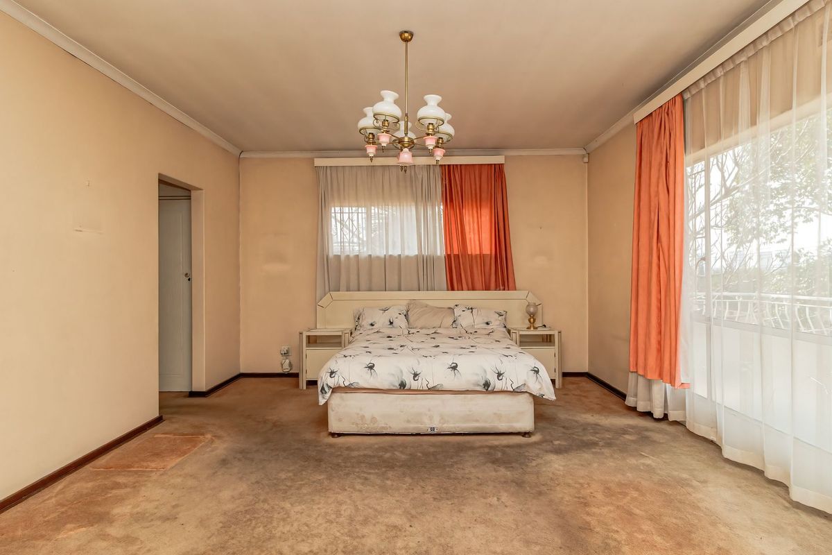 Spacious bedroom featuring a built-in headboard, large sliding glass door with access to a balcony, and a central ceiling light fixture.