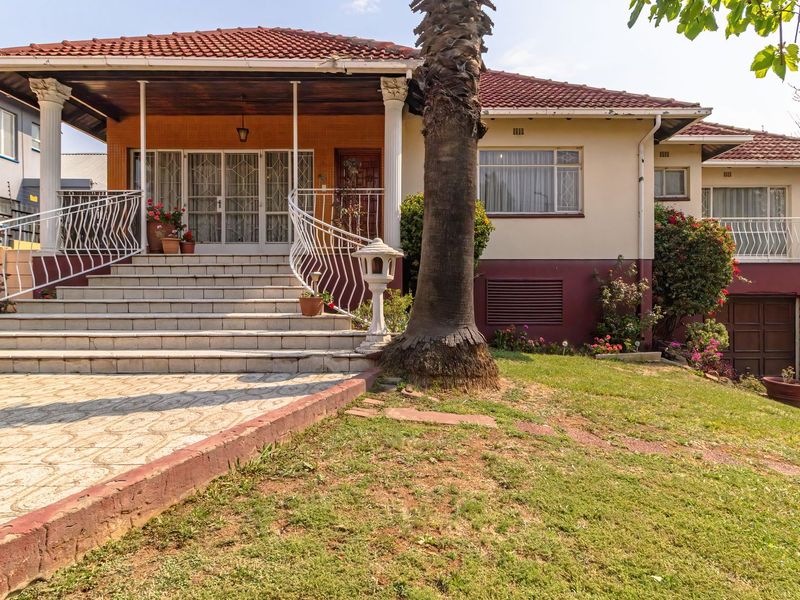 Front elevation of a traditional house featuring a tiled staircase, covered porch with columns, and an integrated garage.