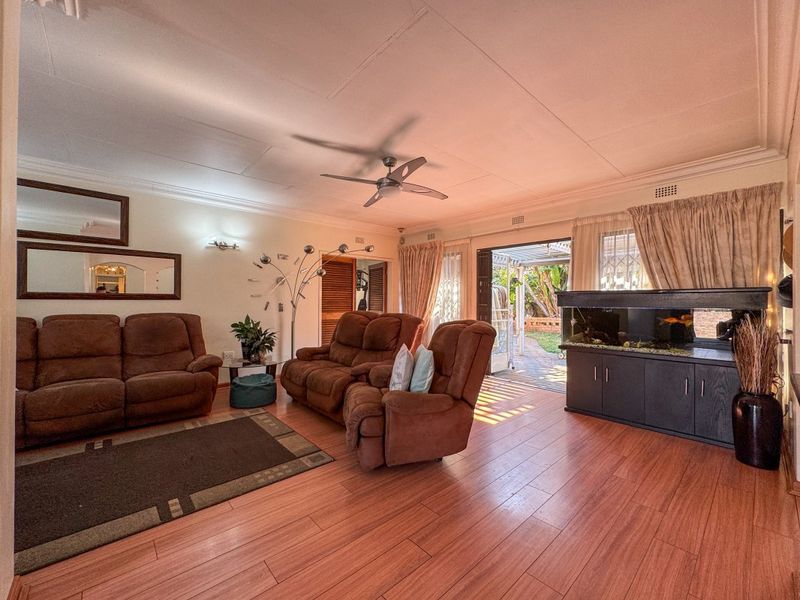A spacious living room featuring laminate flooring, a ceiling fan, and direct access to an outdoor patio area through sliding glass doors.