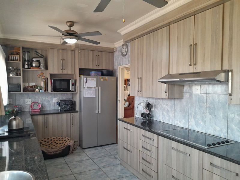 A functional kitchen featuring light wood-grain cabinetry, granite countertops, tiled backsplash, and integrated cooking appliances, offering a practical and well-maintained workspace.