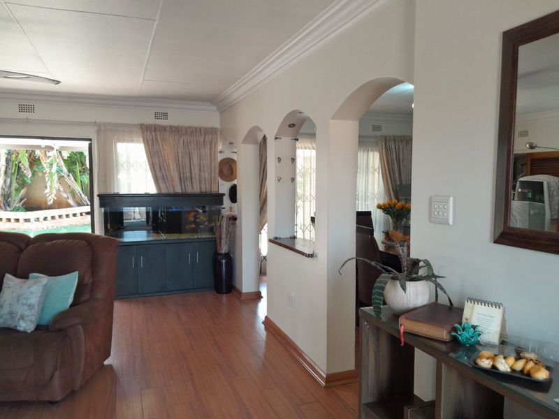 A living area featuring laminate flooring, decorative arched wall openings, and access to the rear garden through a sliding glass door.