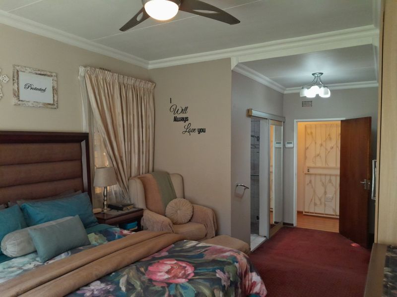 A bedroom featuring a ceiling fan, coving, and an en-suite bathroom access with sliding doors and built-in storage.
