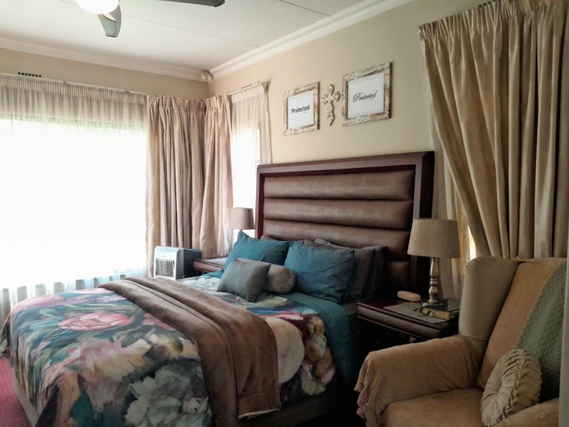 A well-lit bedroom featuring crown molding and a ceiling fan, providing a comfortable and functional sleeping space.