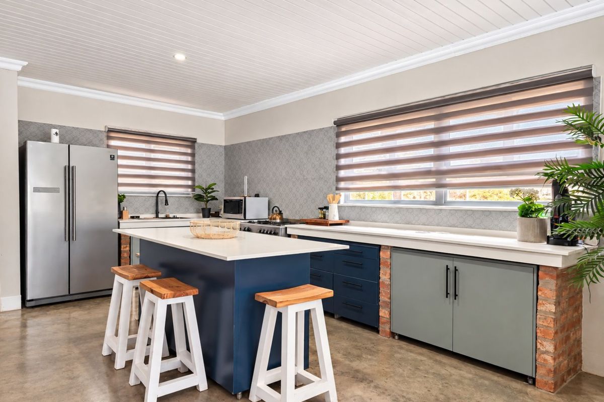 Modern kitchen featuring a central island with quartz countertops, exposed brick accents, custom cabinetry, and a clean tongue and groove ceiling finish.