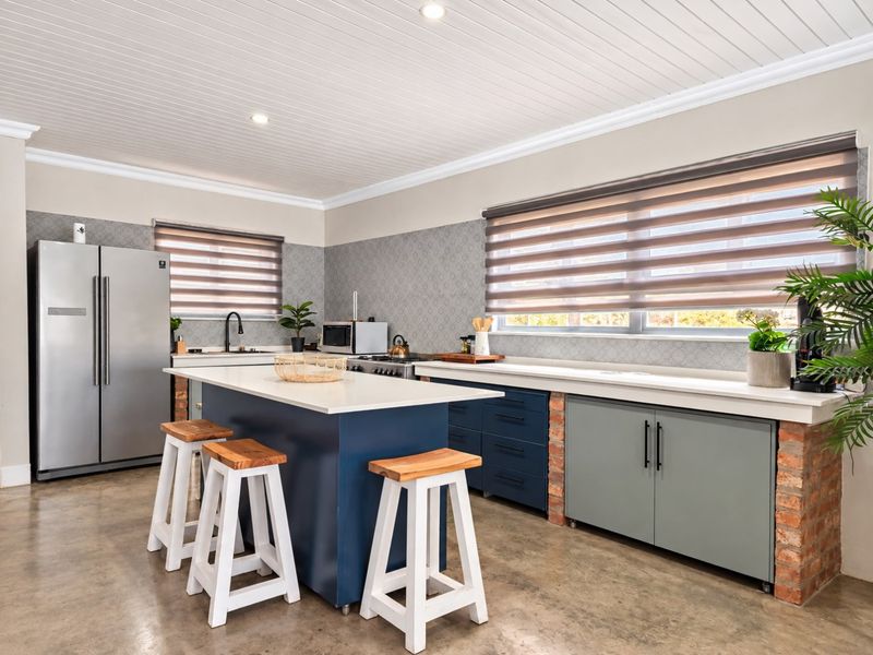 Modern kitchen featuring a central island with quartz countertops, exposed brick accents, custom cabinetry, and a clean tongue and groove ceiling finish.