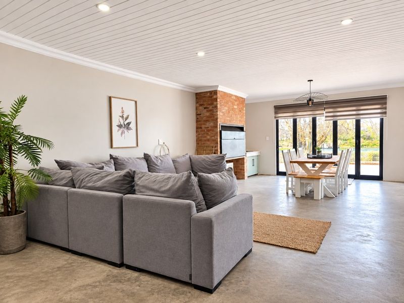 Spacious open-plan living and dining area featuring polished concrete floors, a built-in brick fireplace, and large sliding doors leading to the outdoors.