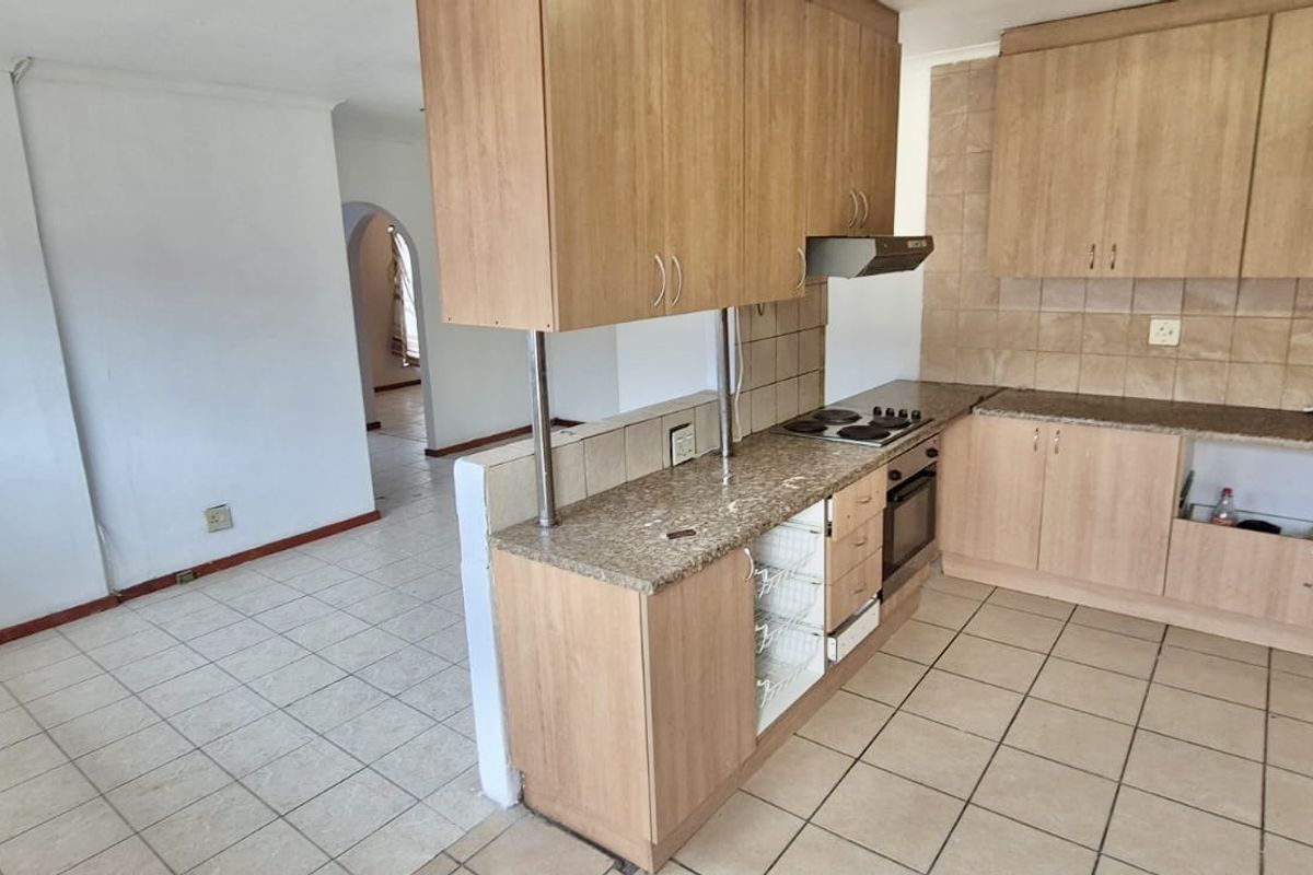 A functional kitchen featuring laminate cabinetry, granite countertops, and built-in appliances, with an open-plan layout connecting to the adjacent living area.