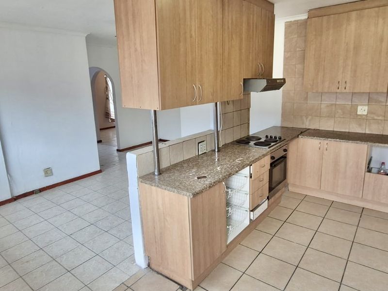 A functional kitchen featuring laminate cabinetry, granite countertops, and built-in appliances, with an open-plan layout connecting to the adjacent living area.