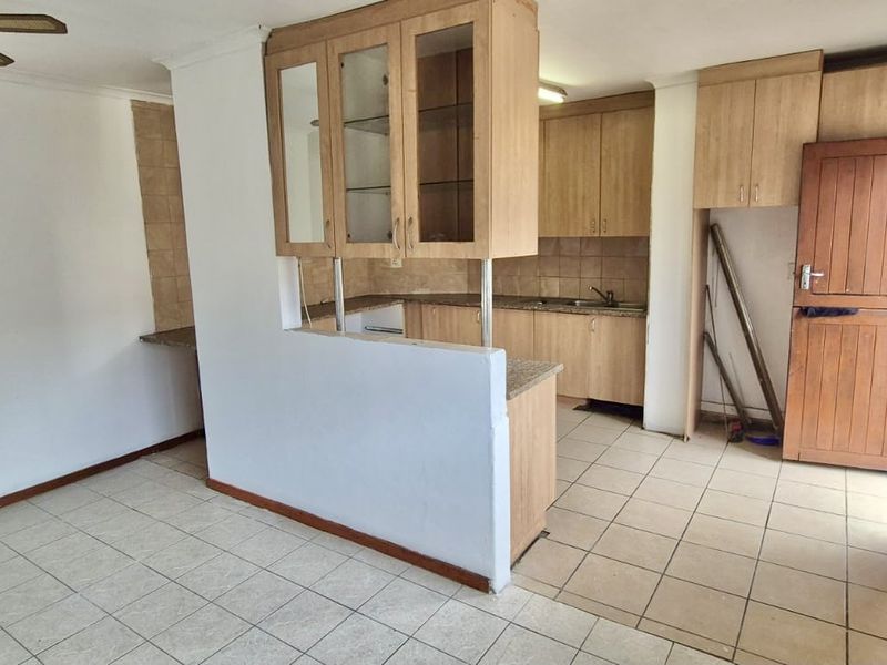 Open plan kitchen and living area featuring tiled floors, timber cabinetry, and a stable door leading to the exterior.