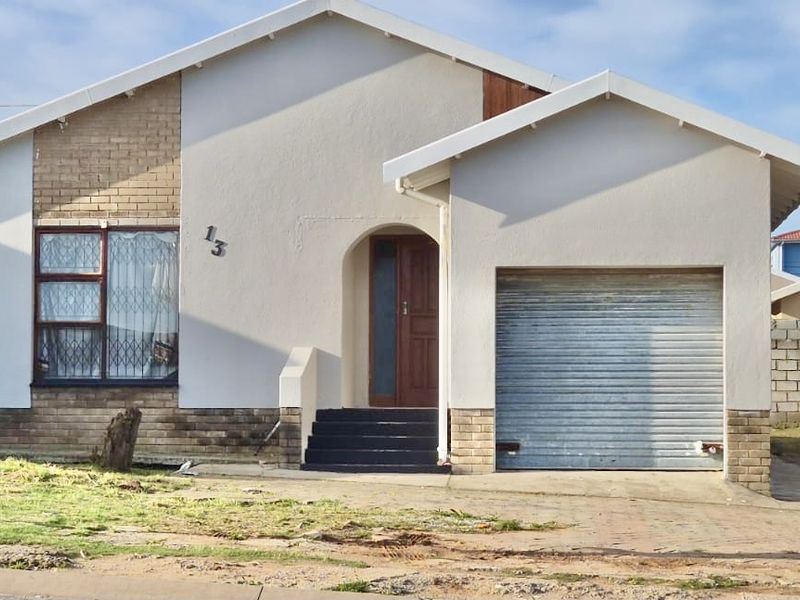 Front elevation of a single-story house featuring a roller shutter garage door, brick and plaster facade, and a covered entrance with concrete steps.