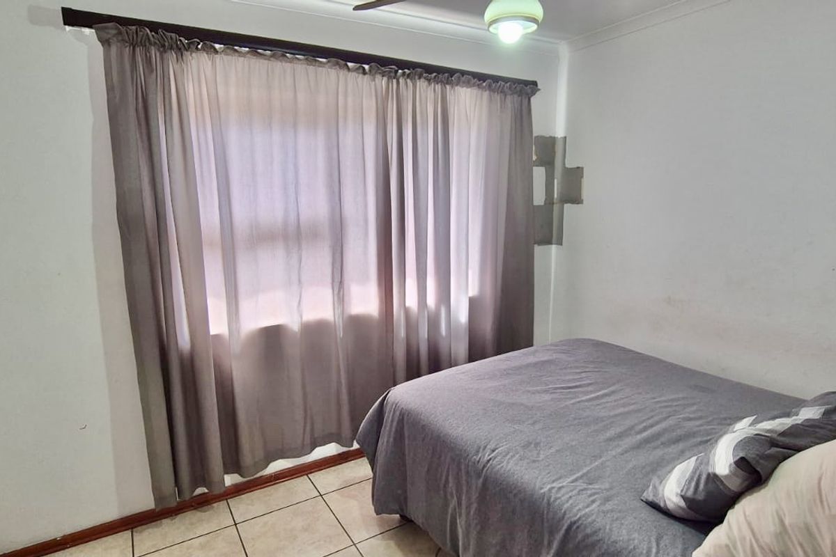 A functional bedroom featuring tiled flooring, a built-in wardrobe, and a ceiling fan, offering a neutral base for personalization.