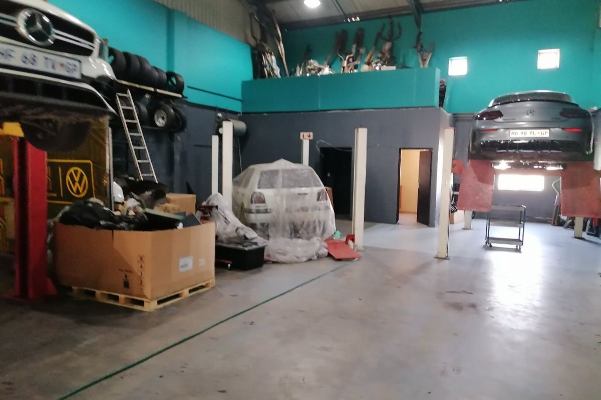 Commercial workshop space featuring vehicle lifts, concrete flooring, and a mezzanine storage area, suitable for automotive repair or industrial operations.