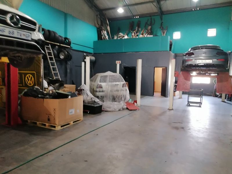 Commercial workshop space featuring vehicle lifts, concrete flooring, and a mezzanine storage area, suitable for automotive repair or industrial operations.