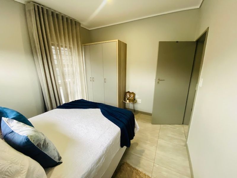 A well-maintained bedroom featuring neutral wall tones, tiled flooring, and a functional built-in wardrobe with ample storage space.