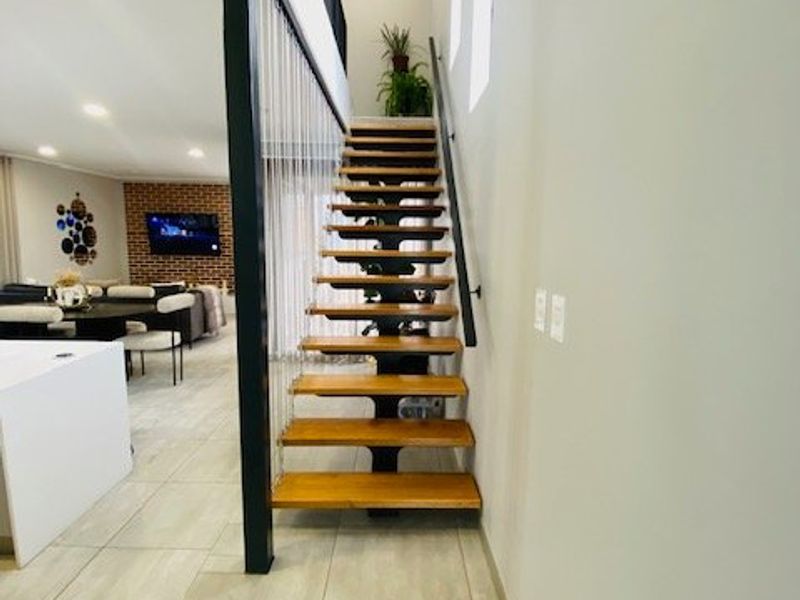 Modern open-tread timber staircase featuring a sleek steel stringer and cable balustrade, connecting the living area to the upper level.