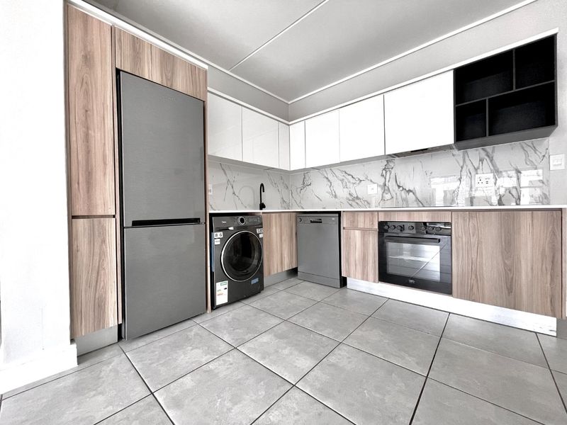 Modern kitchen featuring wood-grain and white cabinetry, marble-look splashback, tiled flooring, and integrated oven with sleek contemporary finishes.