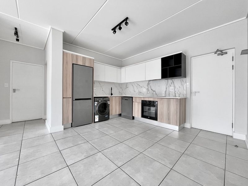 Modern kitchen featuring sleek two-tone cabinetry, marble-look backsplash, integrated oven, and neutral tiled flooring in an open-plan layout.