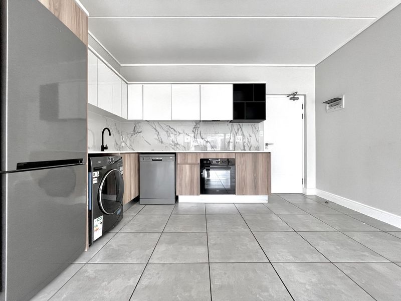 Modern kitchen featuring sleek white and wood-grain cabinetry, marble-look splashback, integrated oven, and durable grey floor tiles in an open-plan layout.