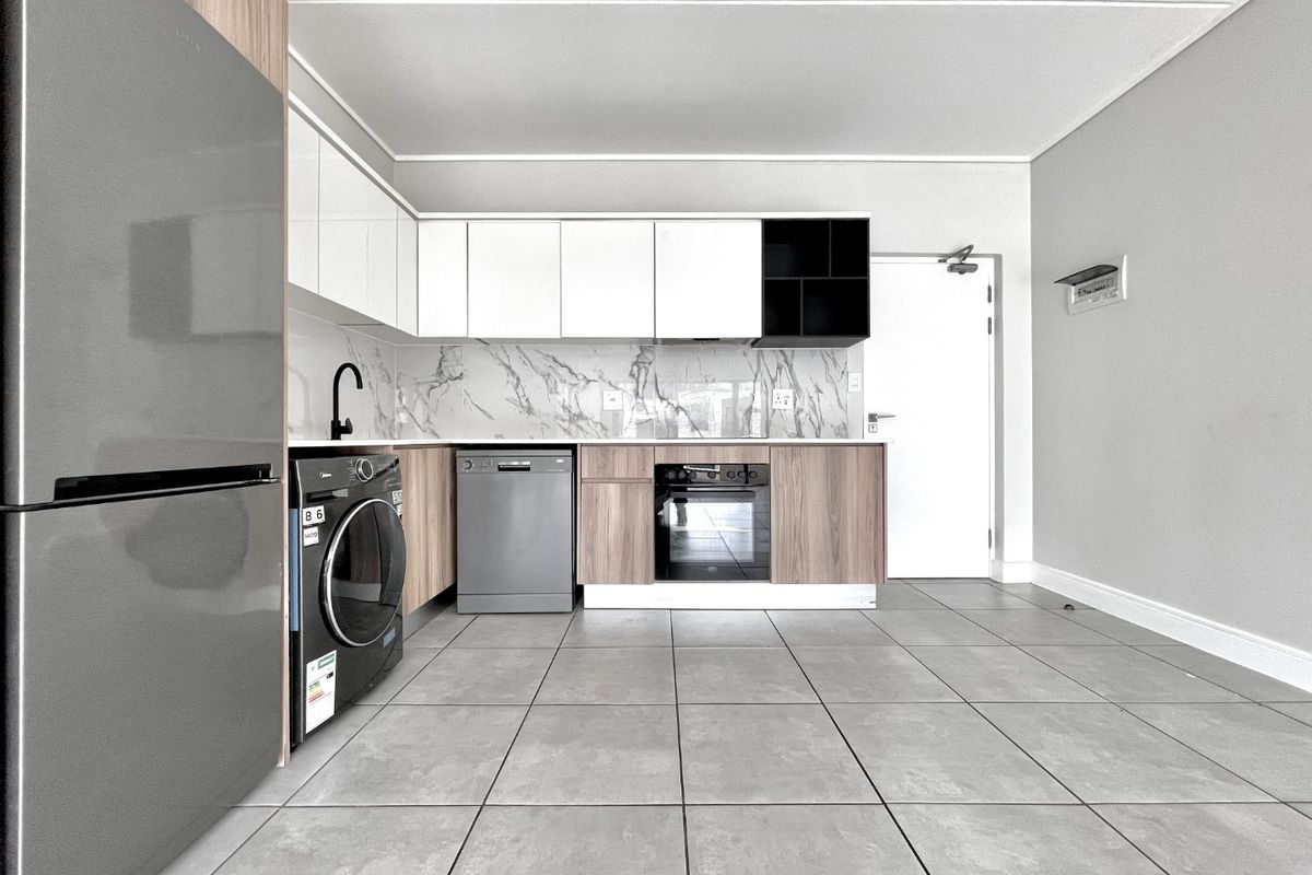 Modern kitchen featuring sleek white and wood-grain cabinetry, marble-look splashback, integrated oven, and durable grey floor tiles in an open-plan layout.