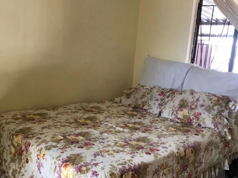 A bedroom featuring a window with security bars and coving, requiring cosmetic updates to the wall finishes.
