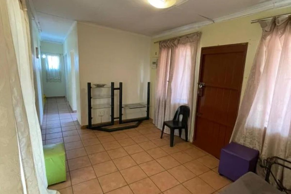A living room area featuring tiled flooring and a coved ceiling, providing a functional space with potential for cosmetic updates.