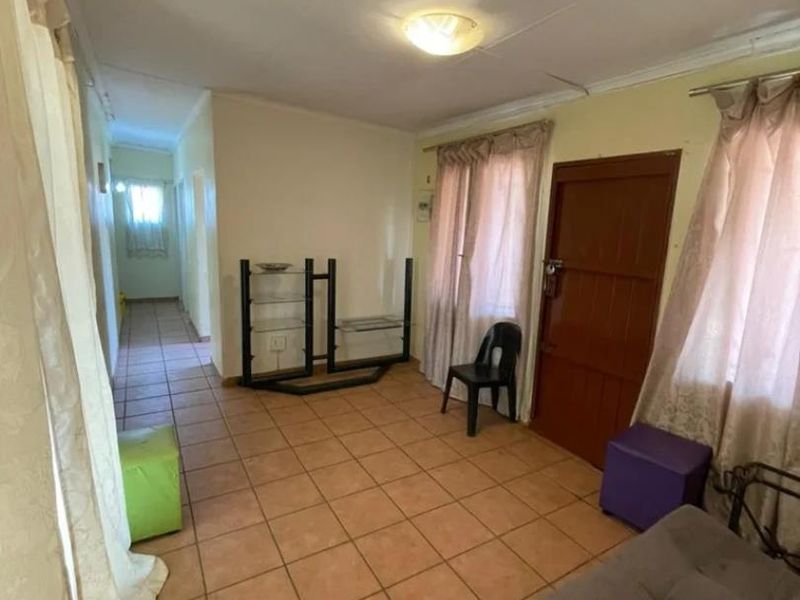 A living room area featuring tiled flooring and a coved ceiling, providing a functional space with potential for cosmetic updates.