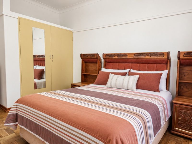 A bedroom featuring classic parquet flooring, a built-in wardrobe with a mirror, and traditional picture rail detailing.