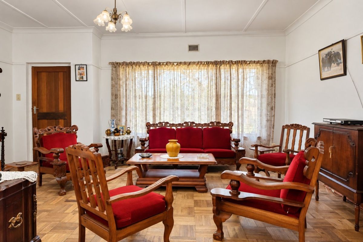 A traditional living room featuring classic parquet flooring, a timber door, and original picture rails, offering a solid foundation for modern updates.