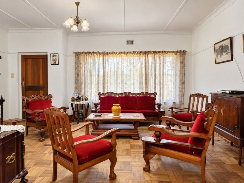 A traditional living room featuring classic parquet flooring, a timber door, and original picture rails, offering a solid foundation for modern updates.