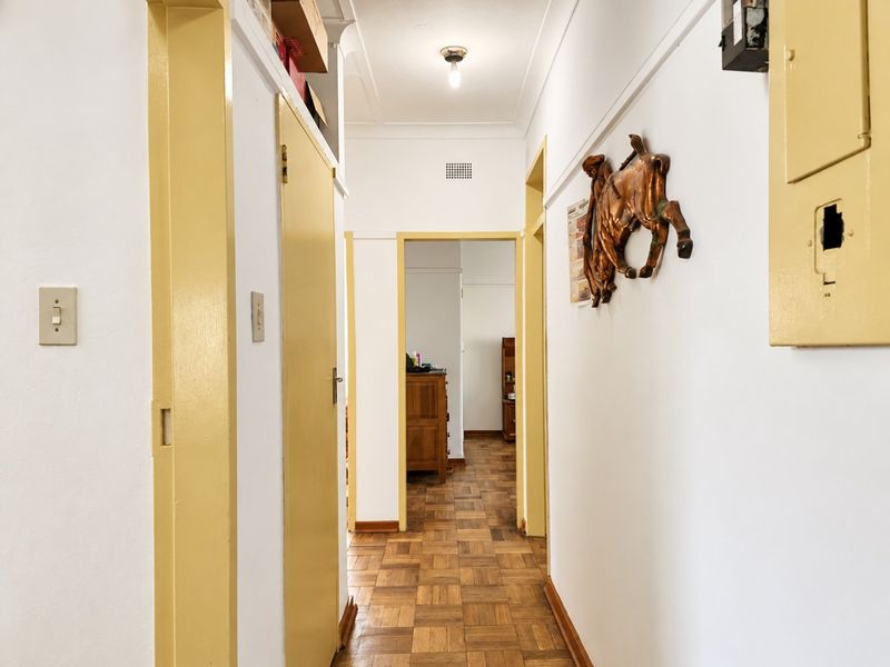 A functional hallway featuring original parquet flooring, coved cornicing, and multiple doorways leading to adjacent rooms.