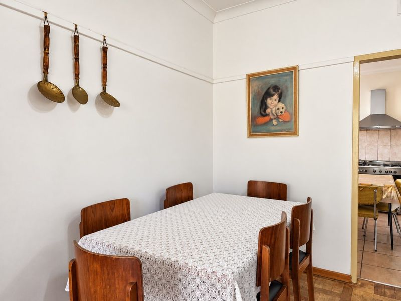Dining room featuring parquet flooring, coved ceilings, and a picture rail, with a view through to the adjacent kitchen area.