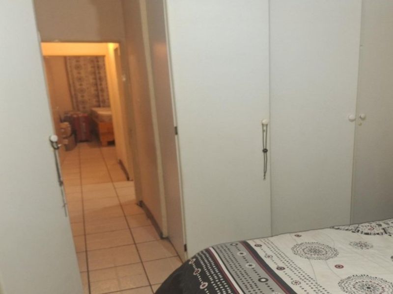 Bedroom featuring built-in cupboards and tiled flooring, with a view leading into an adjacent room.
