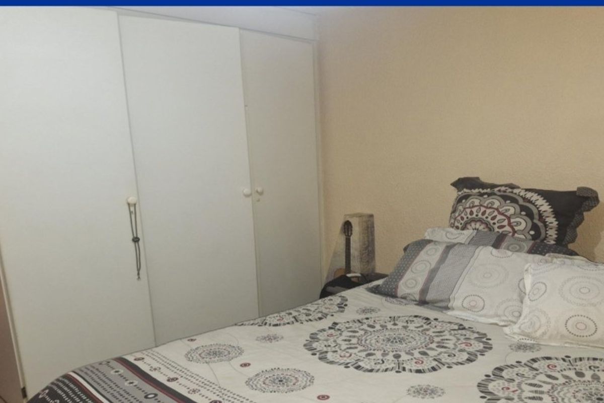 A bedroom featuring a white built-in wardrobe with simple hardware and textured wall finishes.