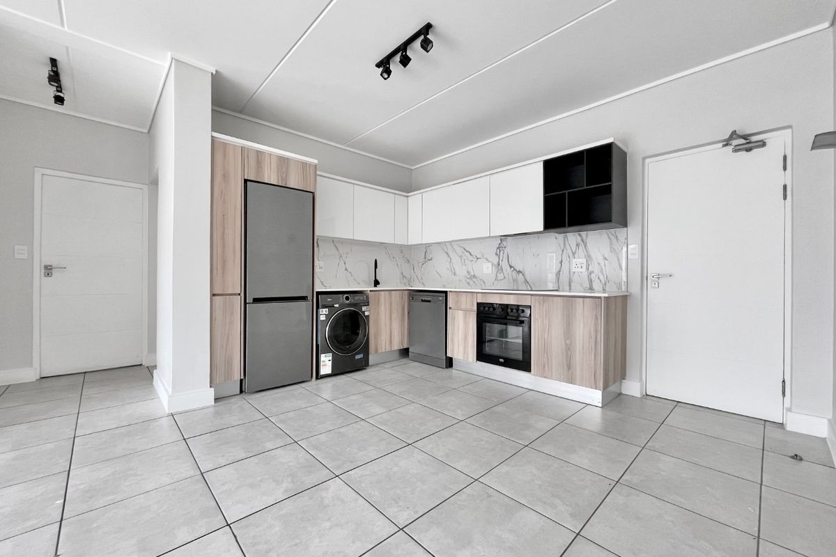 Modern kitchen featuring sleek two-tone cabinetry, marble-look backsplash, integrated oven, and neutral tiled flooring in an open-plan layout.