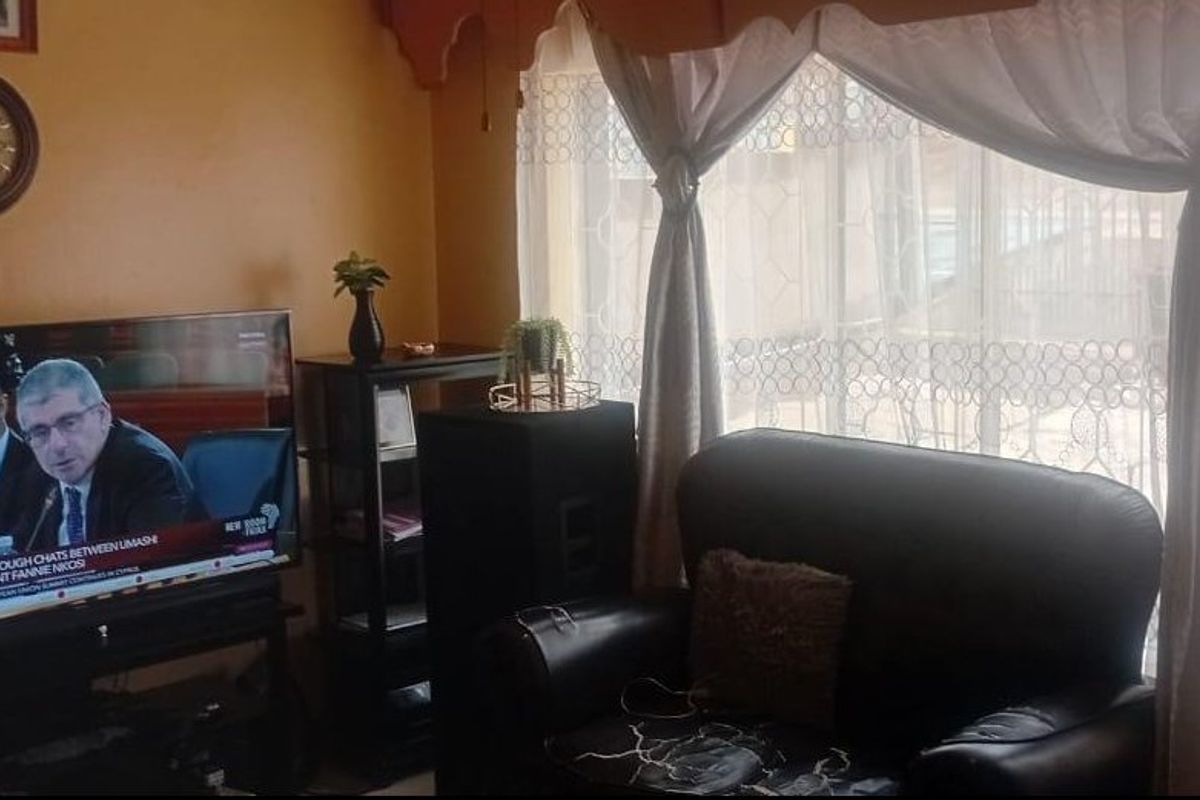 A living room area featuring a large window with curtains, providing natural light to the space.