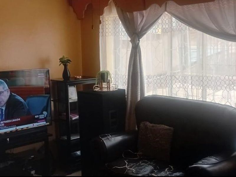 A living room area featuring a large window with curtains, providing natural light to the space.