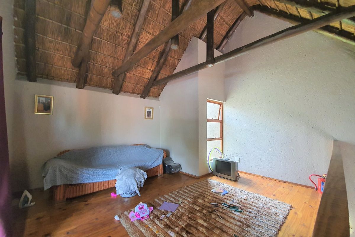 A bedroom featuring a high-pitched thatched ceiling with exposed timber rafters and warm timber flooring, offering a rustic and spacious atmosphere.