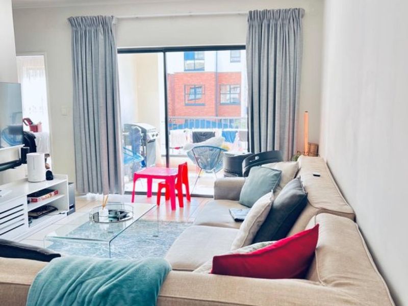 A comfortable living room featuring a large sliding glass door that opens onto a balcony, providing natural light and access to outdoor space.