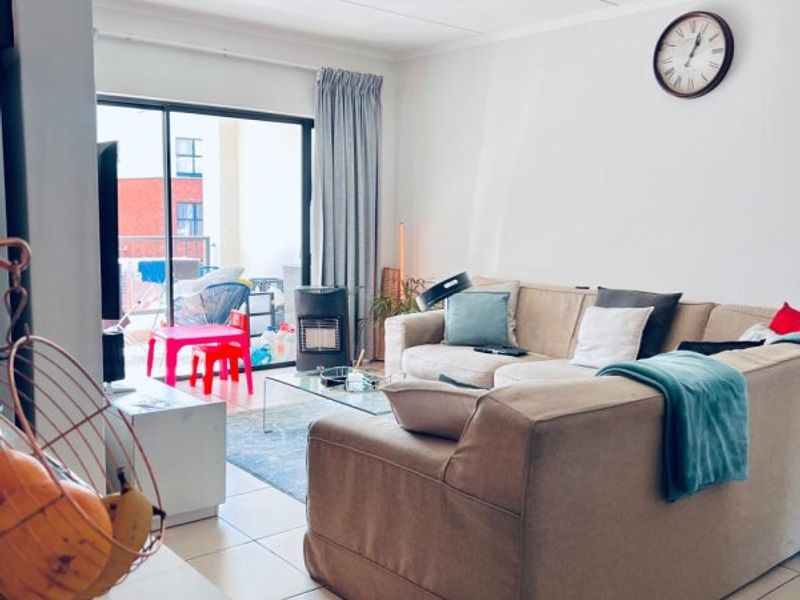 A bright living room featuring tiled flooring and a large sliding glass door providing access to an outdoor patio area.